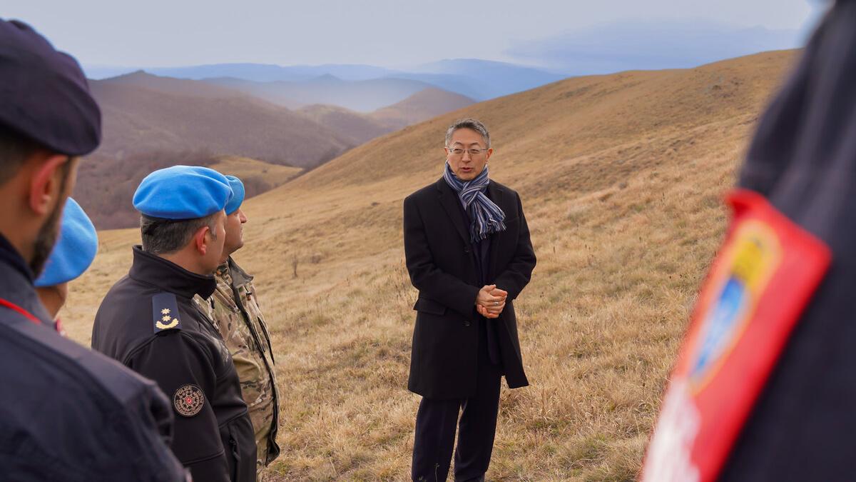 Deputy Special Representative of the Secretary-General and OiC UNMIK Milbert Dongjoon Shin led a delegation of peacekeepers to the site of the 1999 plane crash to pay tribute to the victims. peacekeepers standing in field for rememberance event