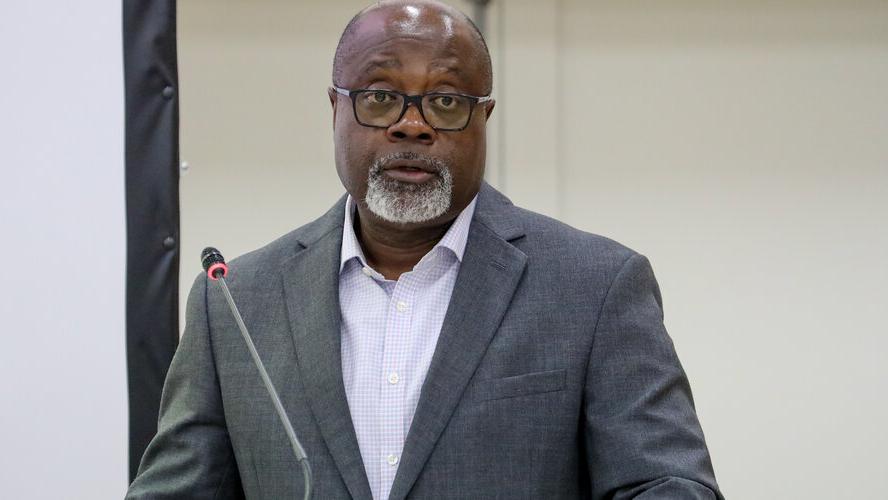A man standing at a lectern and addressing the audience with a microphone.