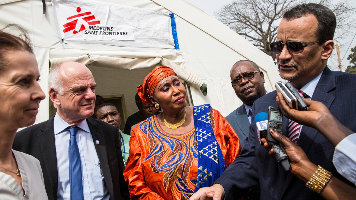 Ismail Ould Cheikh Ahmed (right), Special Representative of the Secretary-General and Head of the UN Mission for Ebola Emergency Response (UNMEER) standing to the right with microphones and recorders near his mouth. Surrounding him are other officials in business attire.