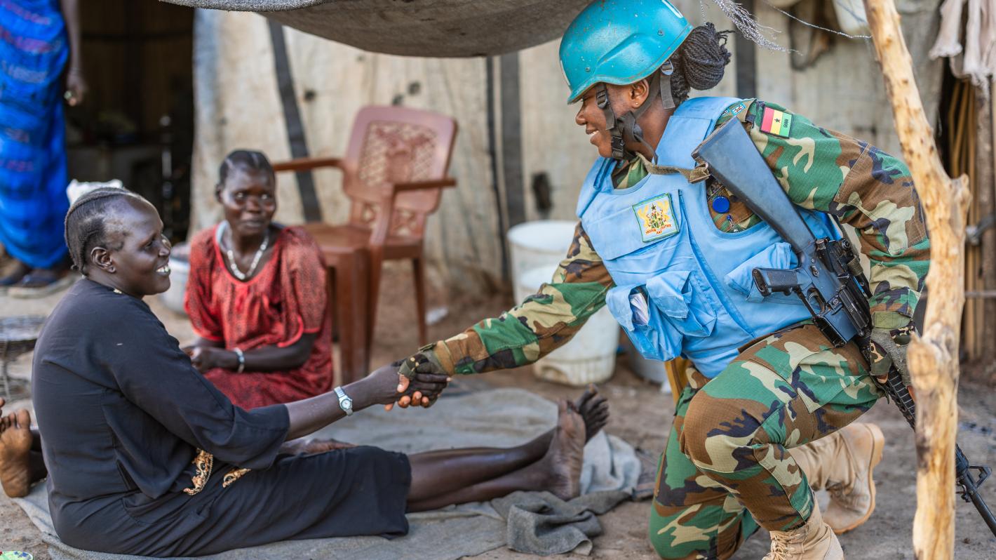 A woman military peacekeeper shakes hands with a member of the community