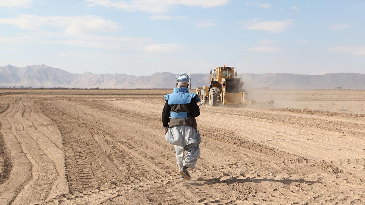 a deminer is in a field with a truck in the background
