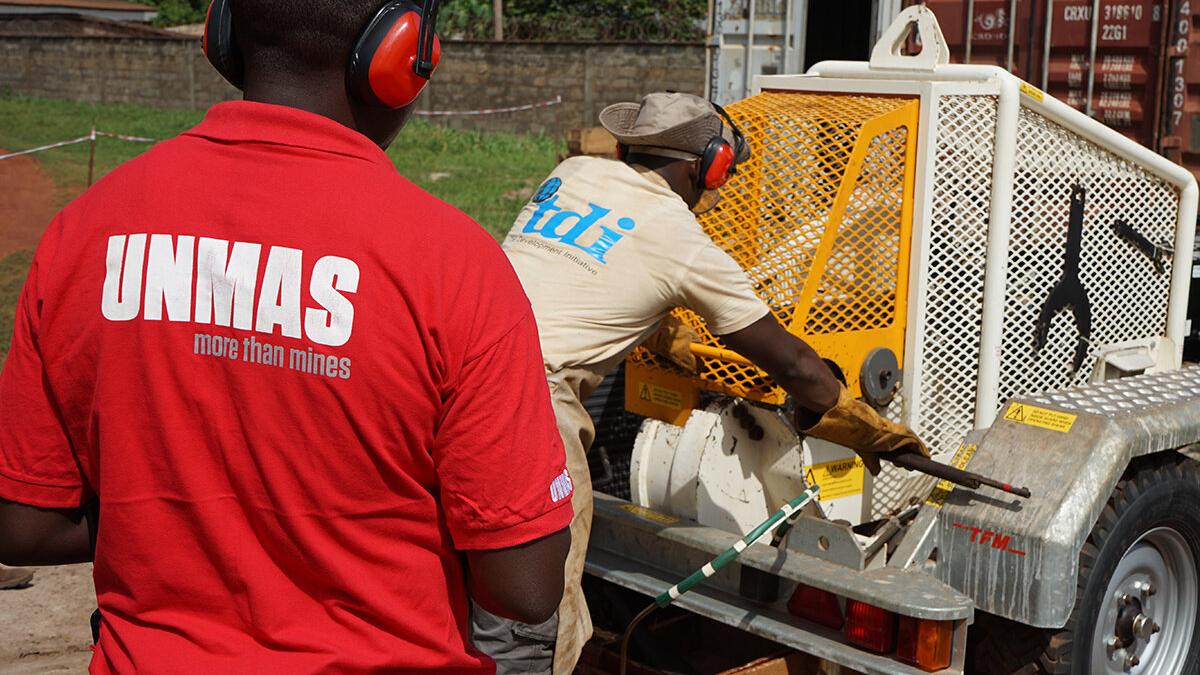 a men with a red T-shirt is standing behind a man conducting weapon destruction