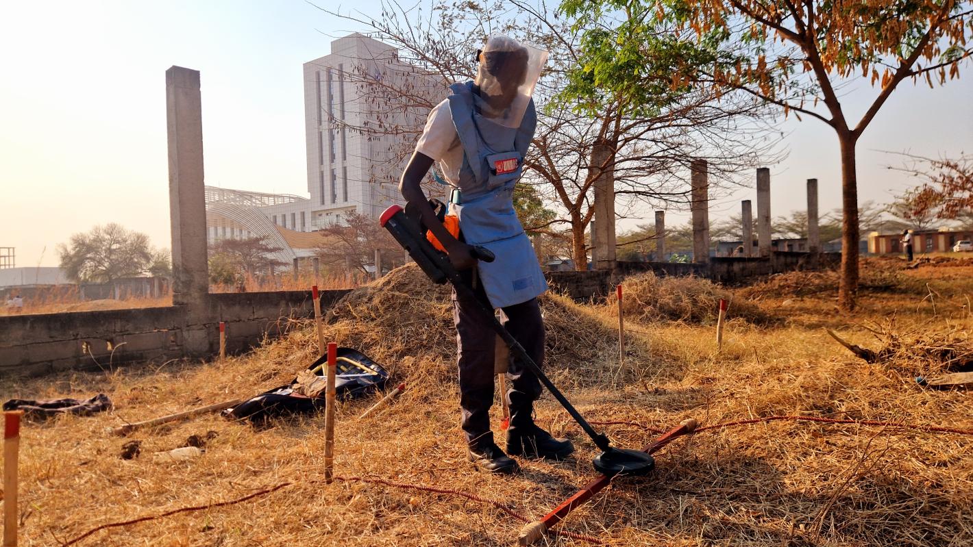 a deminer is deminig the field with a detector