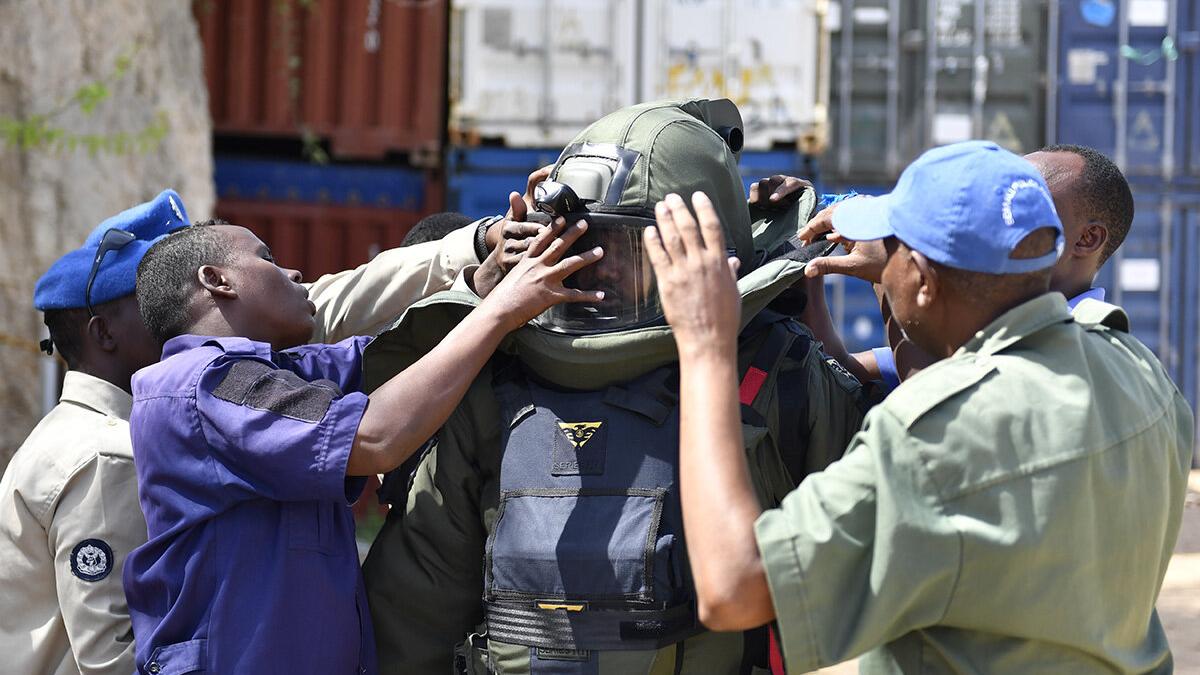 some men are helping a police to wear a protective mask