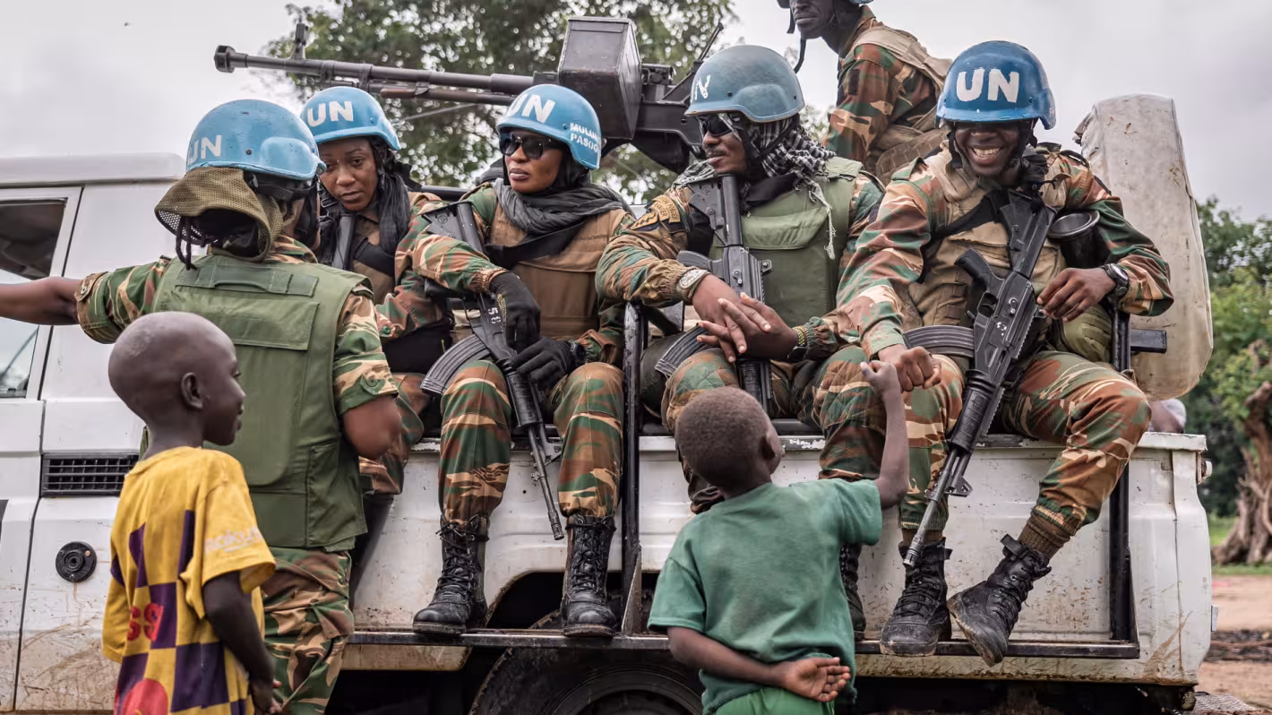 Des casques bleus à bord d'un camion de l'ONU discutent avec des enfants.