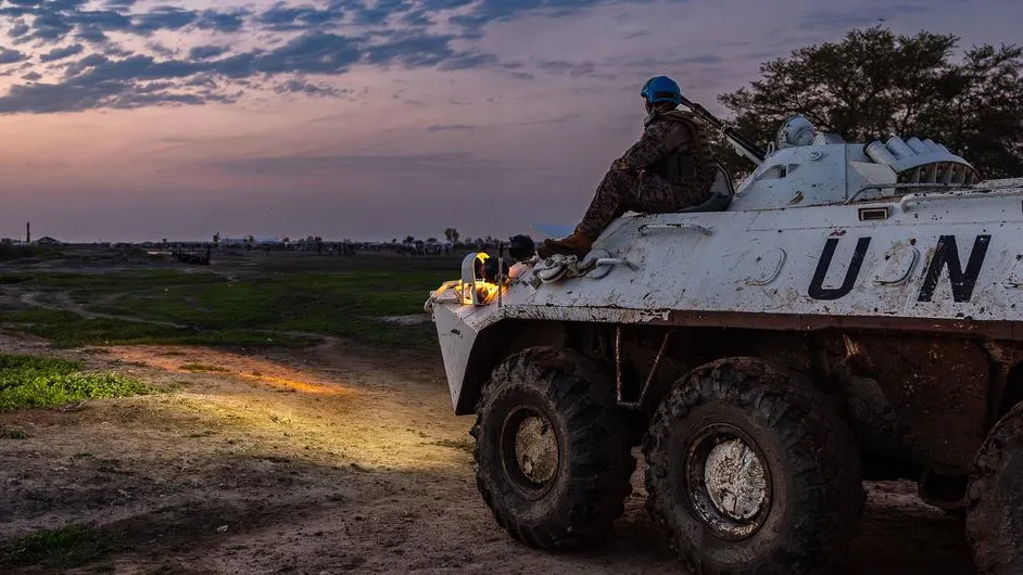 UN peacekeeper sat on a un vehicle staring at sunset.