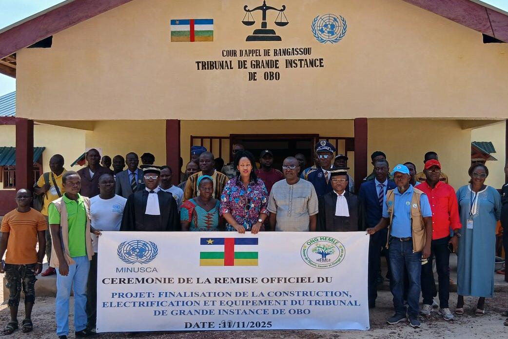 Un groupe de personnes se tient devant un bâtiment, brandissant une grande banderole.