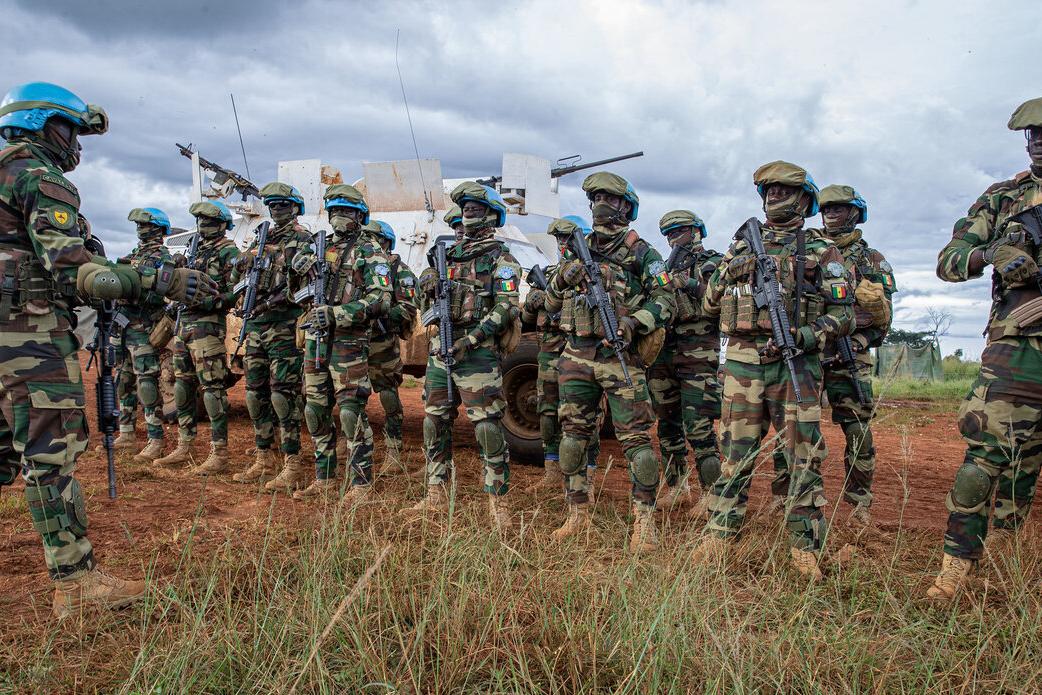 Un groupe de Casques bleus armés de l'ONU se tient en rang, à l'extérieur de leur véhicule.