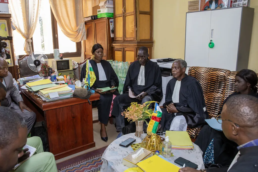 Des juges et un groupe de personnes sont assis dans un bureau et discutent.