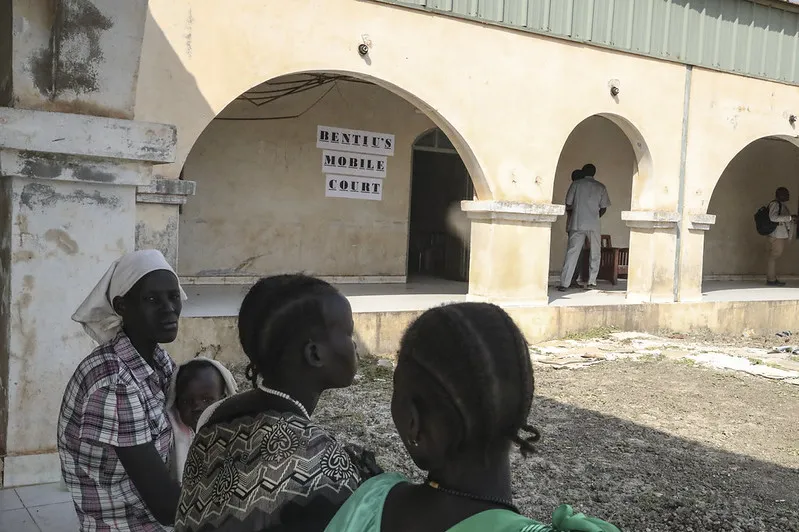 Mujeres sentadas en un banco frente al tribunal móvil de Bentiu.