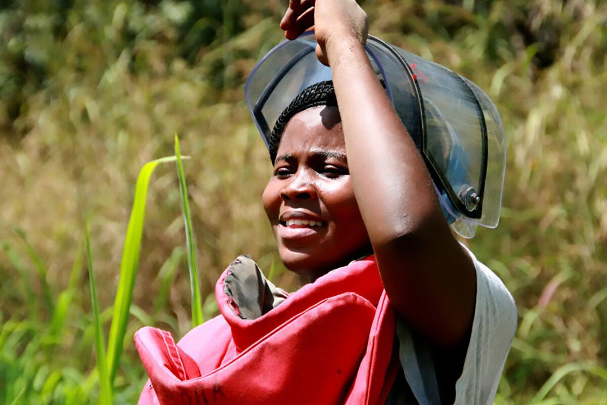 a female deminer is uncovering her mask