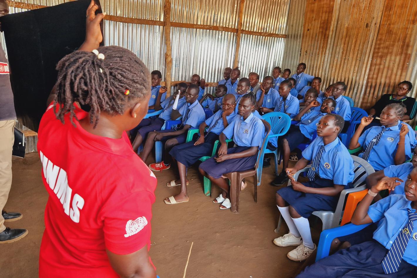 a woman and a man are presenting a poster to a class of students