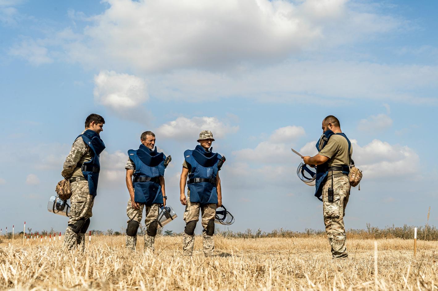 A group of SSTS deminers undergo a briefing before starting work on a potentially contaminated field in the Mykolaiv region.
