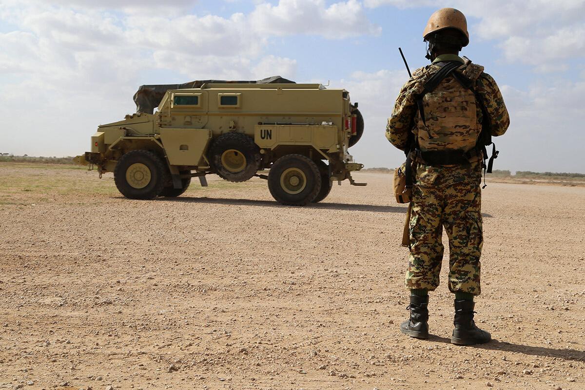 a millitary man is standing in front of a military truck