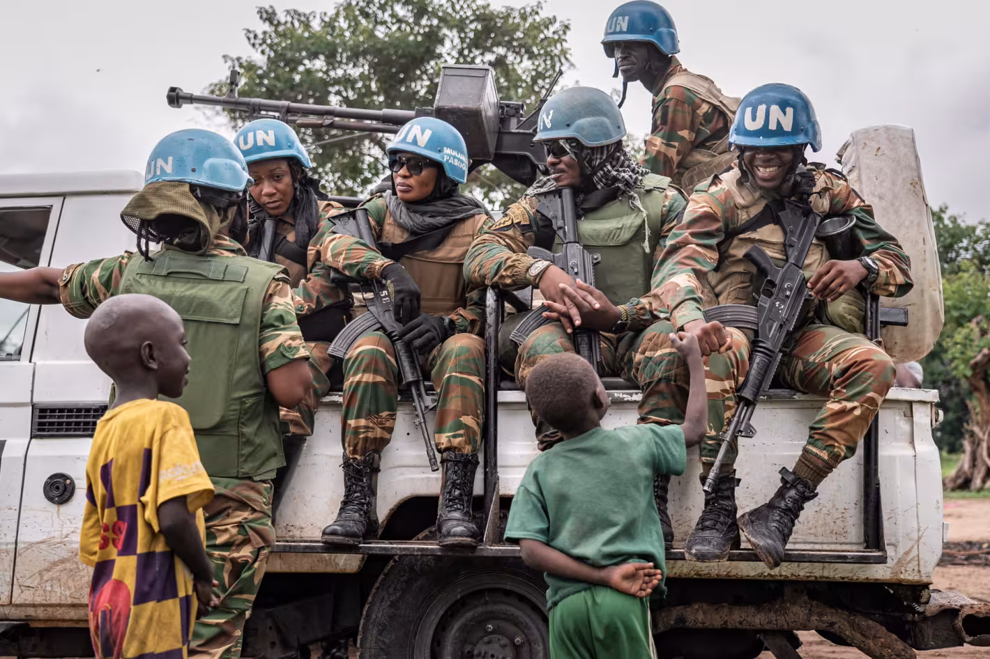 Des casques bleus à bord d'un camion de l'ONU discutent avec des enfants.