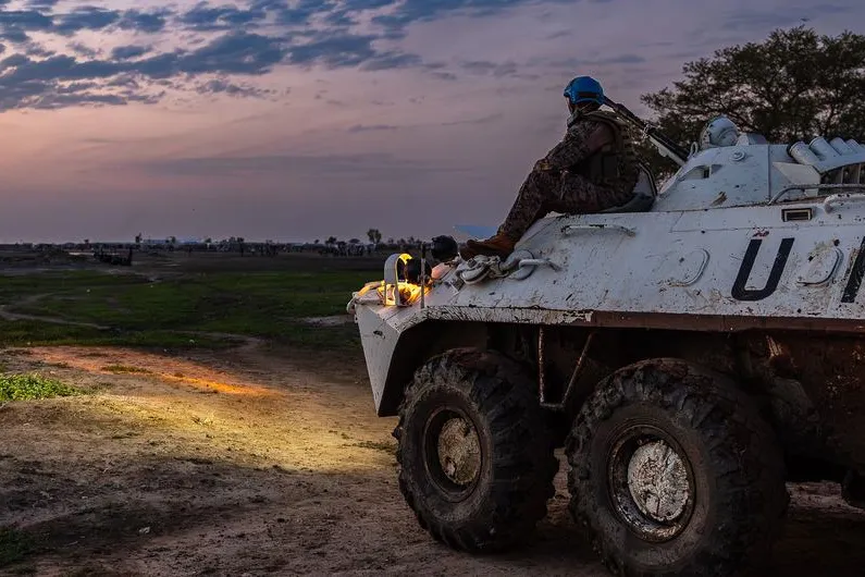 UN  peacekeeper sat on a un vehicle staring at sunset.
