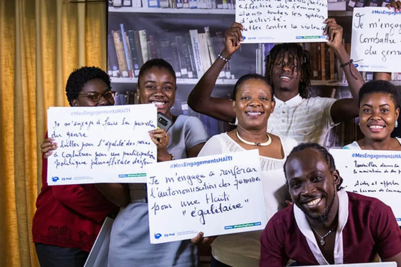 A group of people holding pieces of paper with wording on it smiling