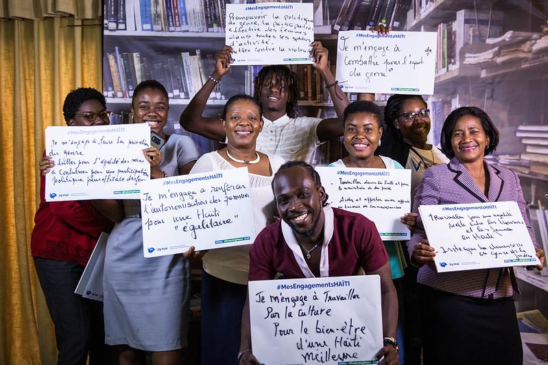 A group of people holding pieces of paper with wording on it smiling