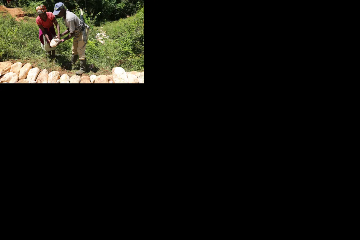 Two people placing a stone in a rock wall.