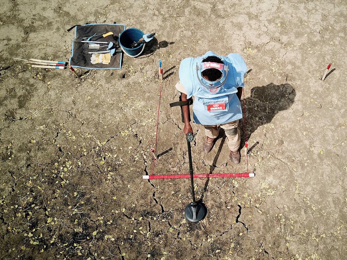 a deminer is deminig the field with a detector