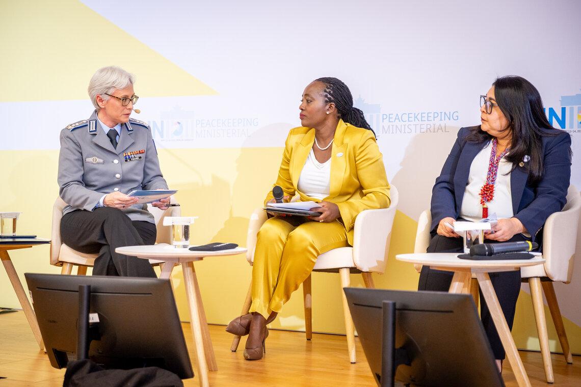 Three women seated in a panel talking to each other. The panel moderator is dressed in military uniform.