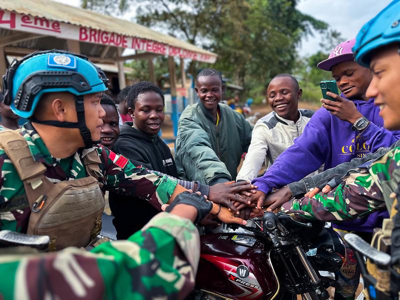 Peacekeepers join hands with young people.